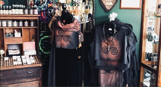 A display of garments in dark colors with a Celtic Triskellion