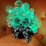 Halloween decoration made from a black cauldron filled with clear plastic bulbs and green lights to simulate bubbling.