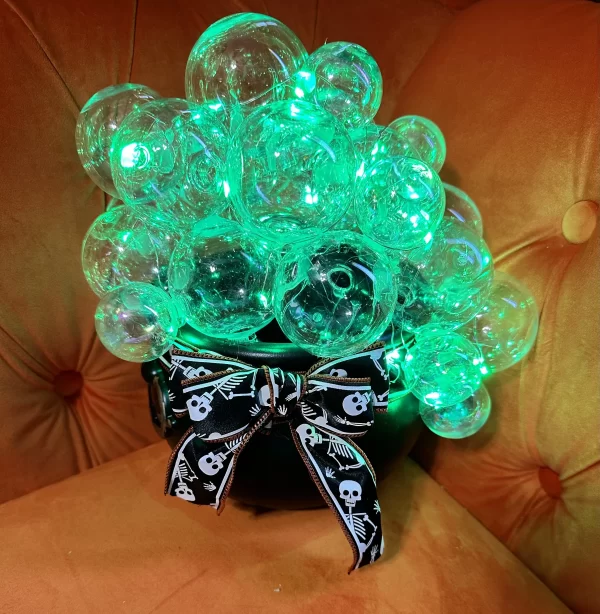 Halloween decoration made from a black cauldron filled with clear plastic bulbs and green lights to simulate bubbling.