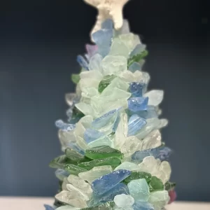 Close-up image of a handmade sea glass Christmas tree, decorated with pieces of blue, green, and clear sea glass, topped with a starfish.