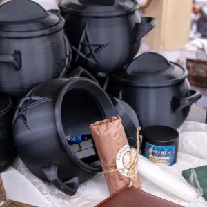 A display of our Beginner Witch Kits ; black 3D-printed Cauldrons with a top that screws into place an containing as selection of items